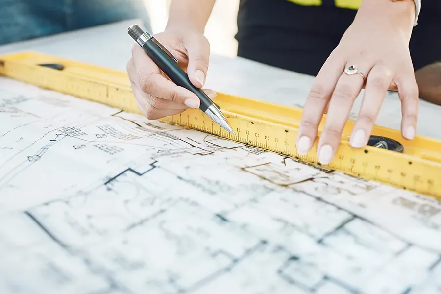Electrician working on the electrical design of new builds, whilst using a spirit level and pen.