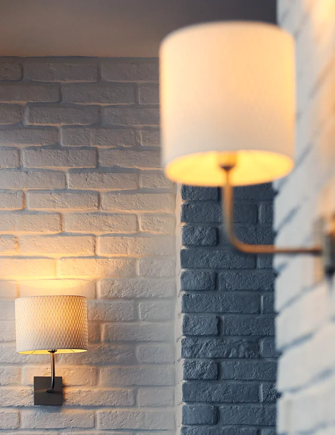 Interior lights with shades mounted on a brick wall.