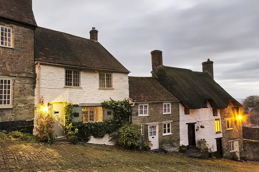 Electrical safety in older properties - A row of period cottages at dusk with cobbled path and road.