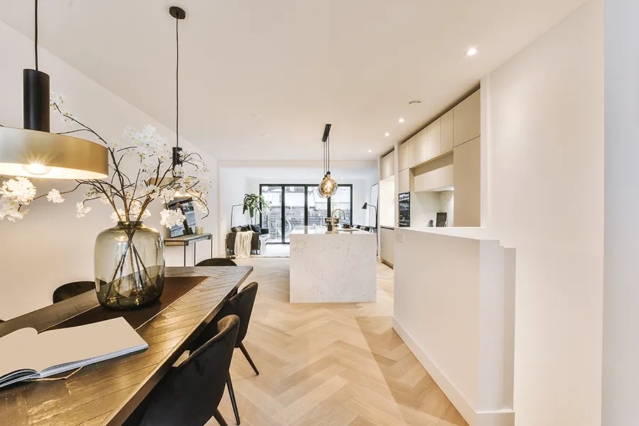 A bright open plan kitchen dining room with kitchen island, dining table and modern lighitng.