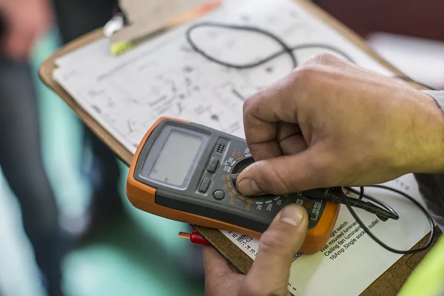 Electrician holding mobile device for testing electrical installations.