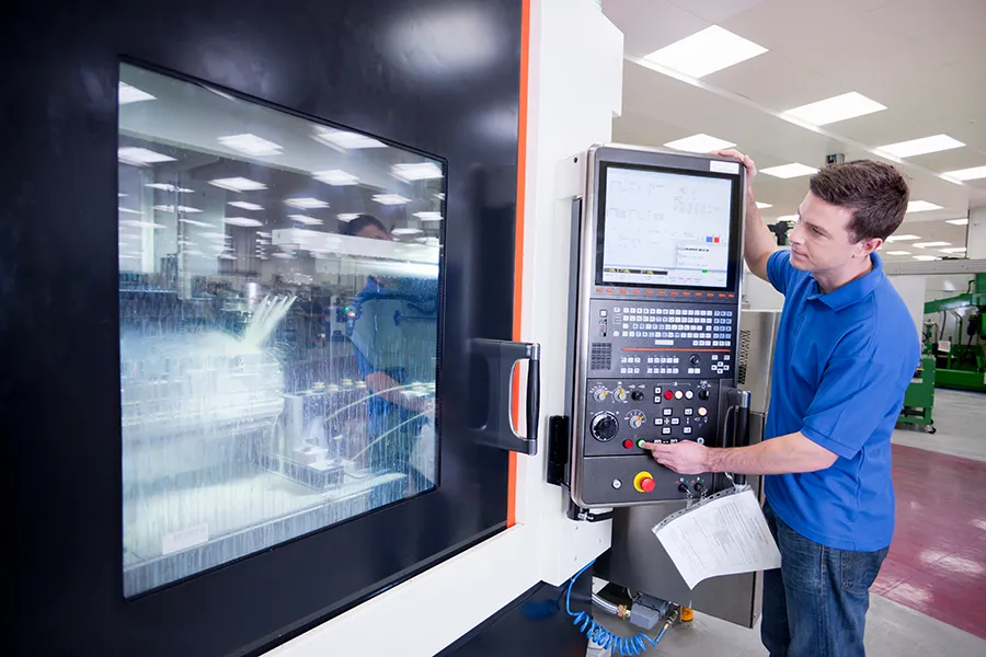 Machinery and Equipment Power Supplies Industrial Power Supply - A factory technican operating a lathe cutting machine using an electric control panel.
