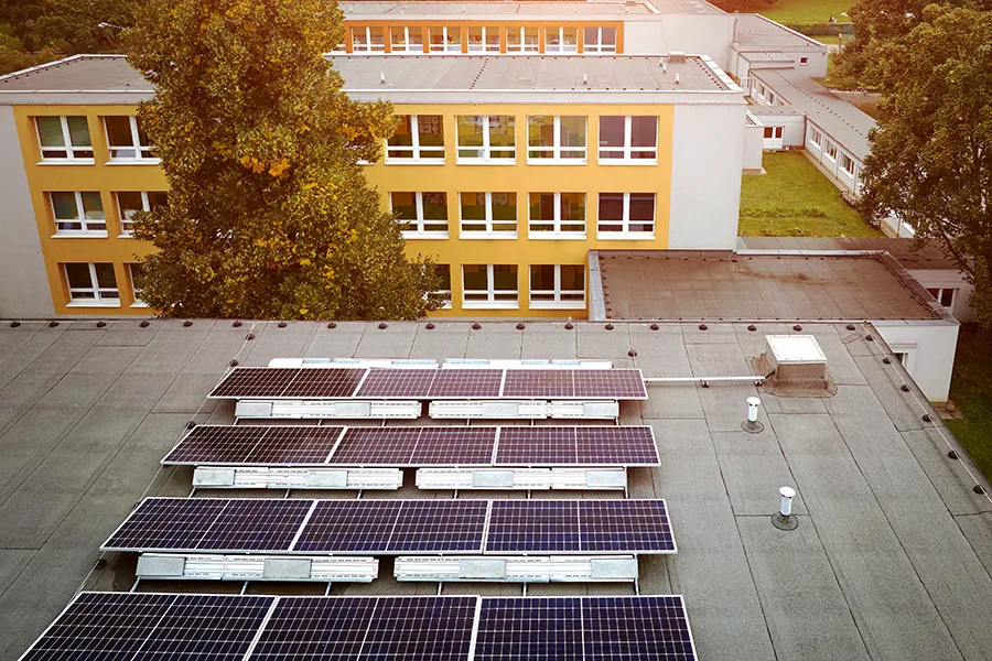 Commercial Solar Panels A bank of solar panels on the the flat roof of a college building.