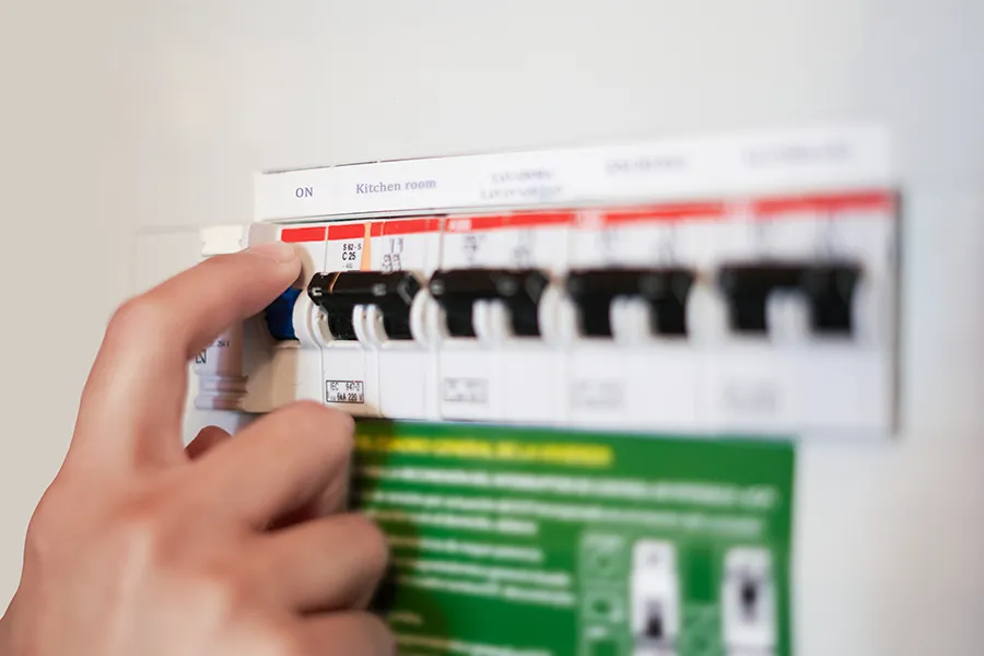 Consumer Unit Upgrades Domestic Electrical Services - A close up of a hand flicking a switch on a consumer unit.
