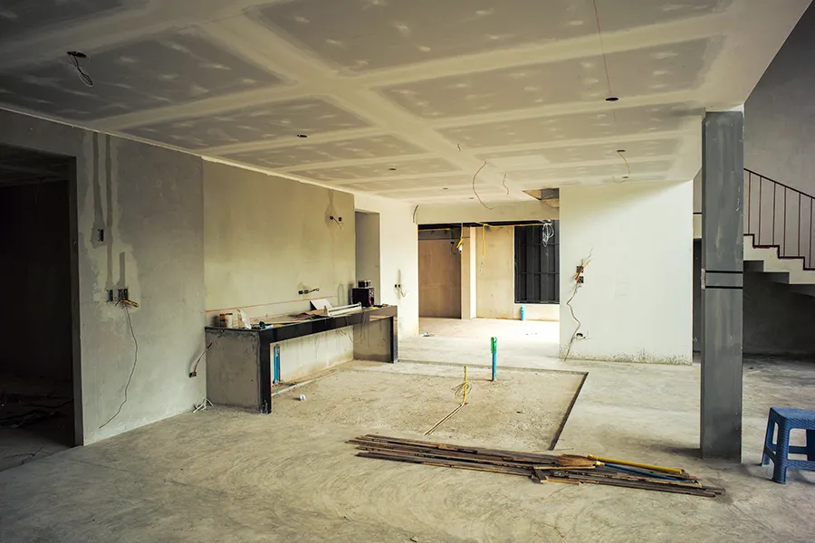 Interior of a room in a house under renovation with electrical wiring showing in ceiling and walls.