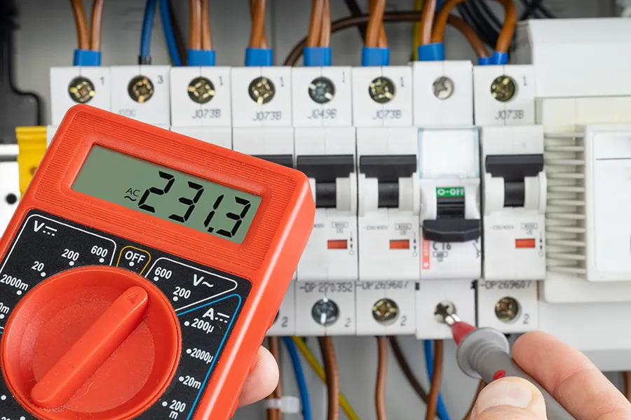 Hand testing electrical circuit with multimeter 