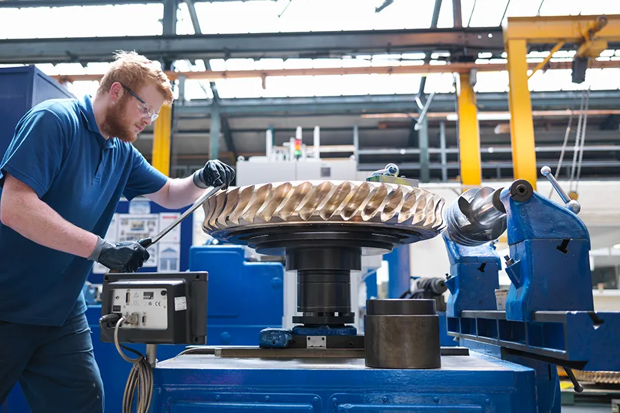 Engineer finishing a bronze gear wheel in a engineering factory.