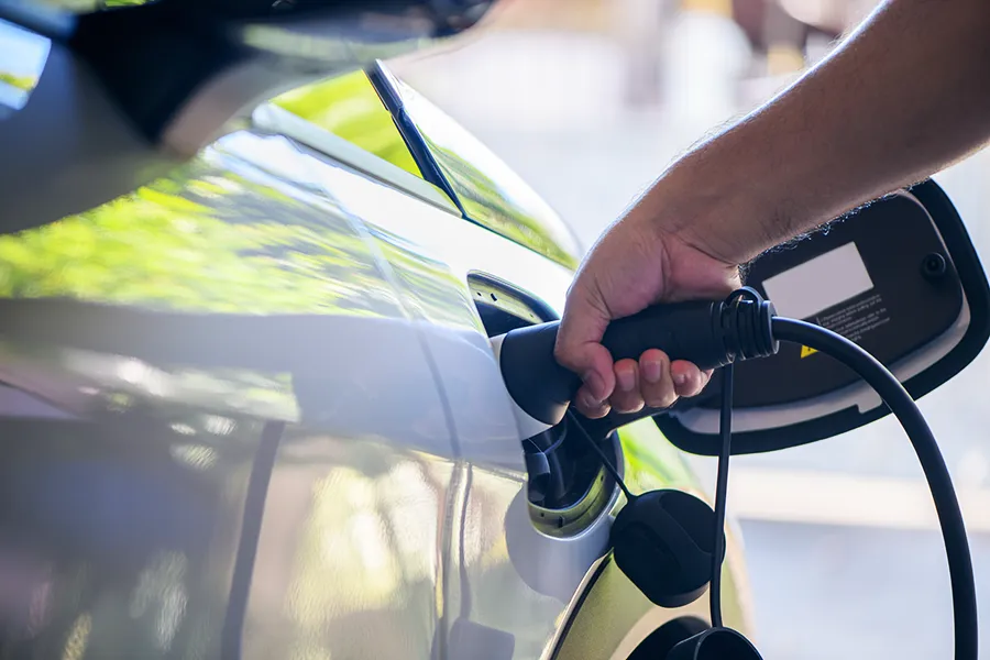 EV Charger Installation EV charger installation - a close up of a man's hand putting charging cable in an electric vehicle.