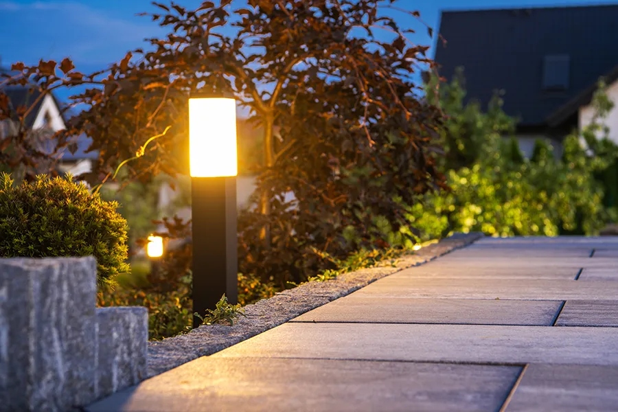 Outdoor garden bollard light on the edge of a patio paved area.