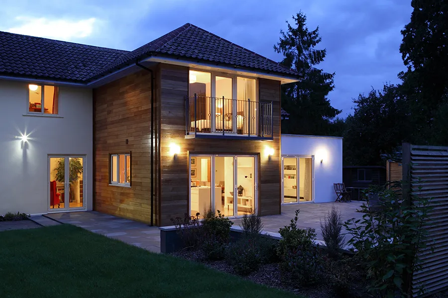 Back of a domestic house illuminated in the evening with garden security lighting.