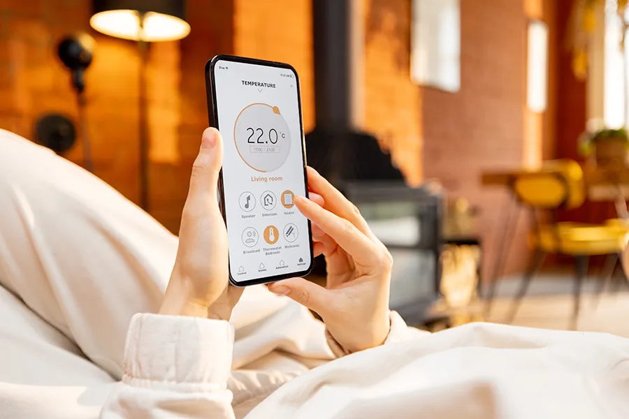 A relaxed woman using her mobile phone with smart home application to change the temperature in her home.