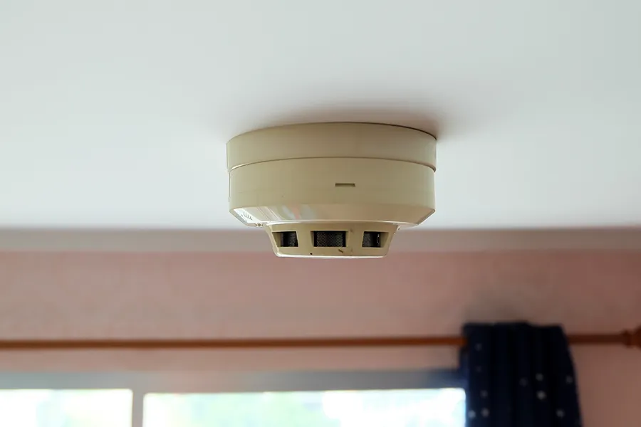 Fire Alarm Installation Close up of a smoke fire alarm on a ceiling in a domestic room.
