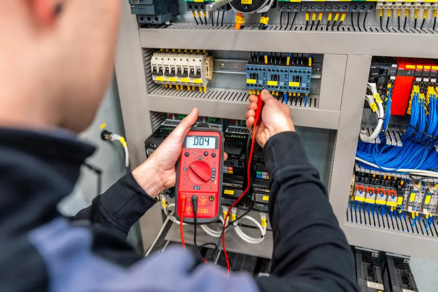 Close-up of a three-phase power installer as he checks a system panel.